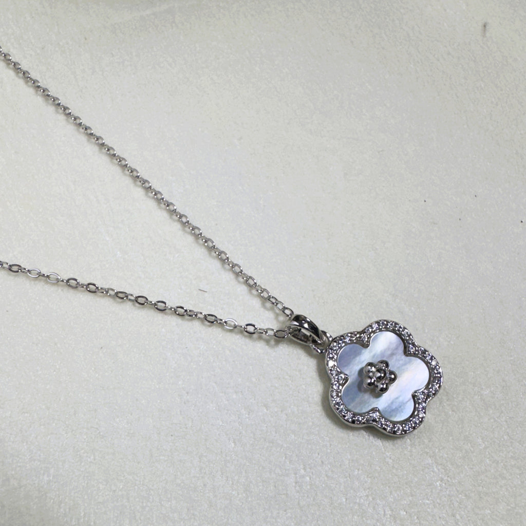 The mother of pearl flower pendant hanging from the silver cable chain.