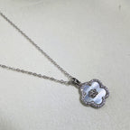 The mother of pearl flower pendant hanging from the silver cable chain.
