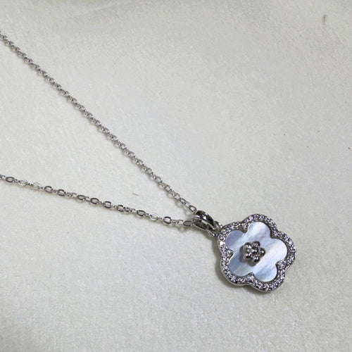 The mother of pearl flower pendant hanging from the silver cable chain.