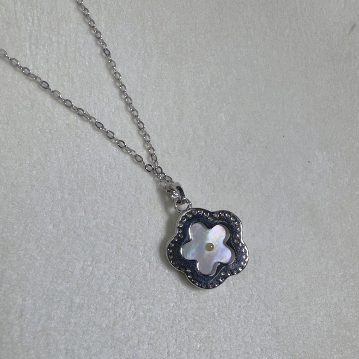 The flower pendant seen from the side on the cable chain.