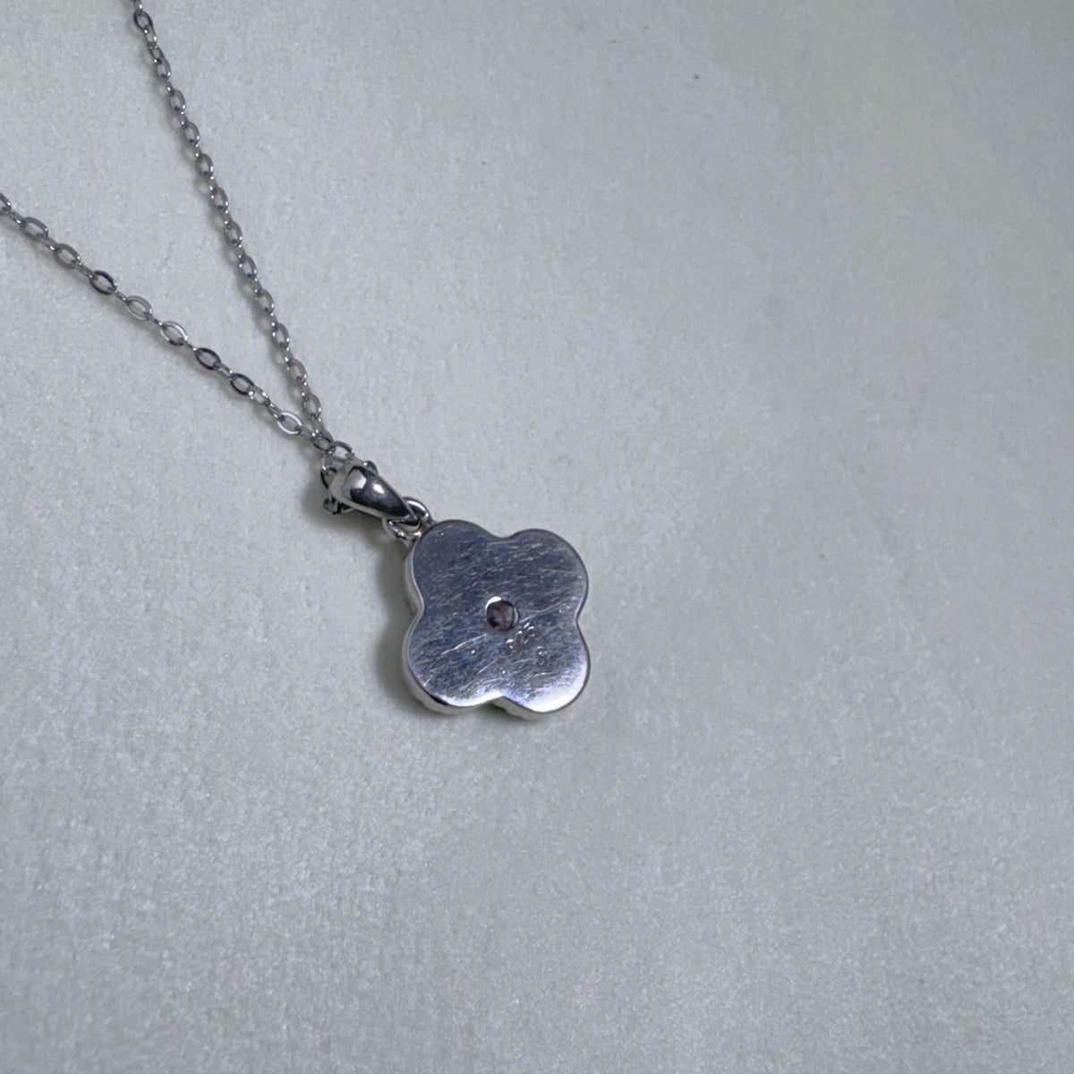 The plain polished back of the flower pendant.