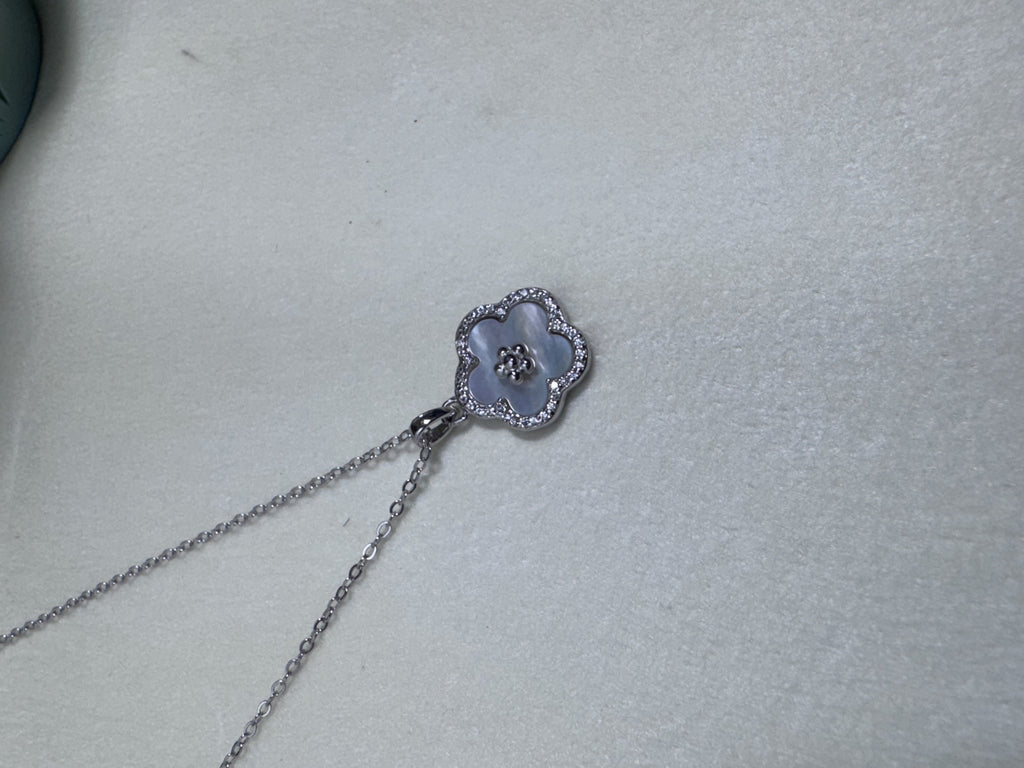 The flower pendant necklace laid out on a pale surface.