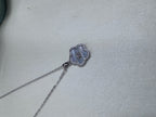 The flower pendant necklace laid out on a pale surface.