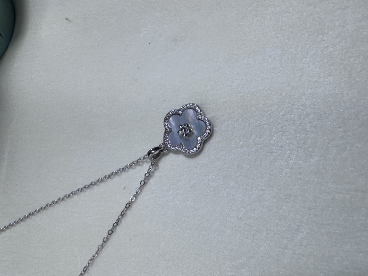 The flower pendant necklace laid out on a pale surface.