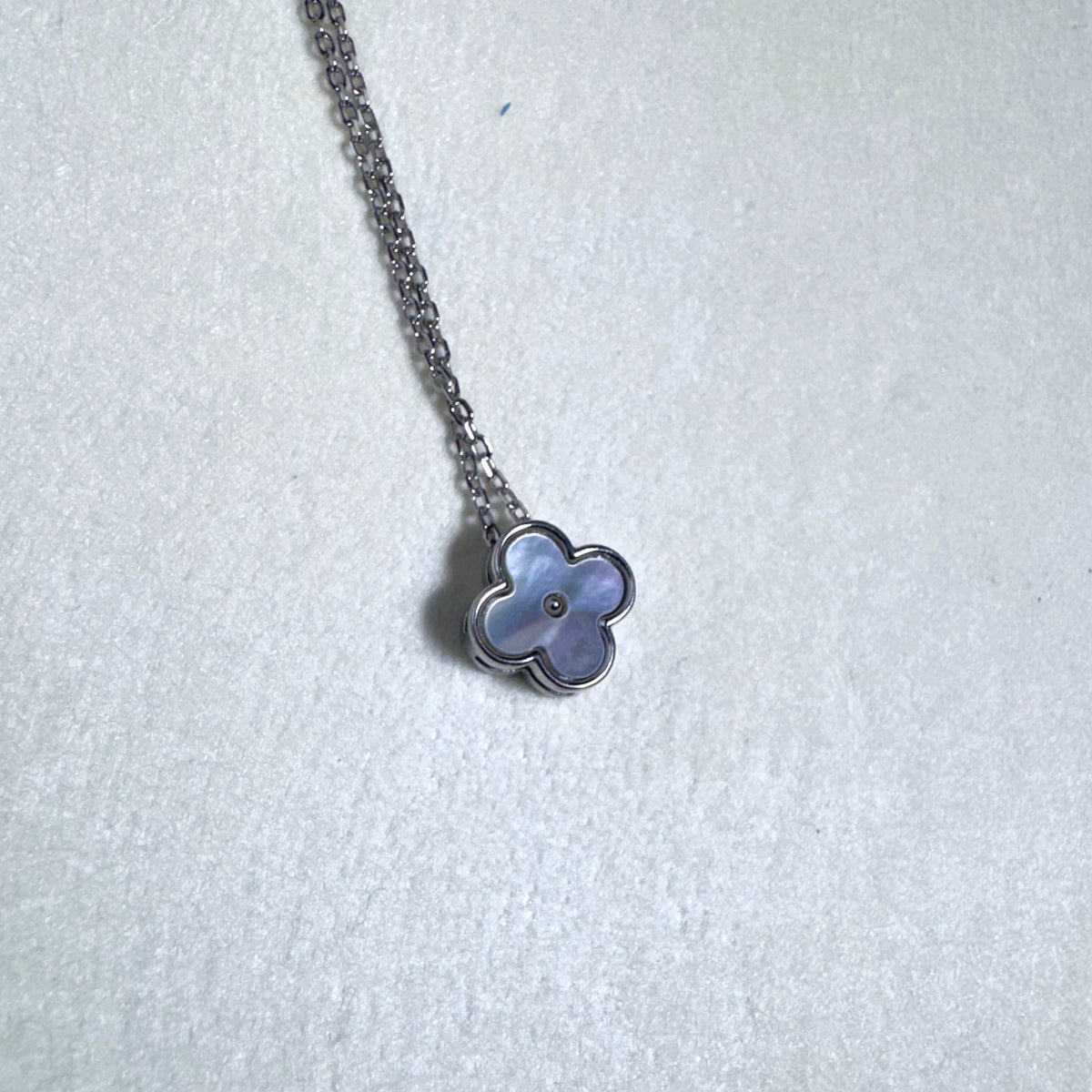 The mother of pearl clover slider hanging from the silver chain.