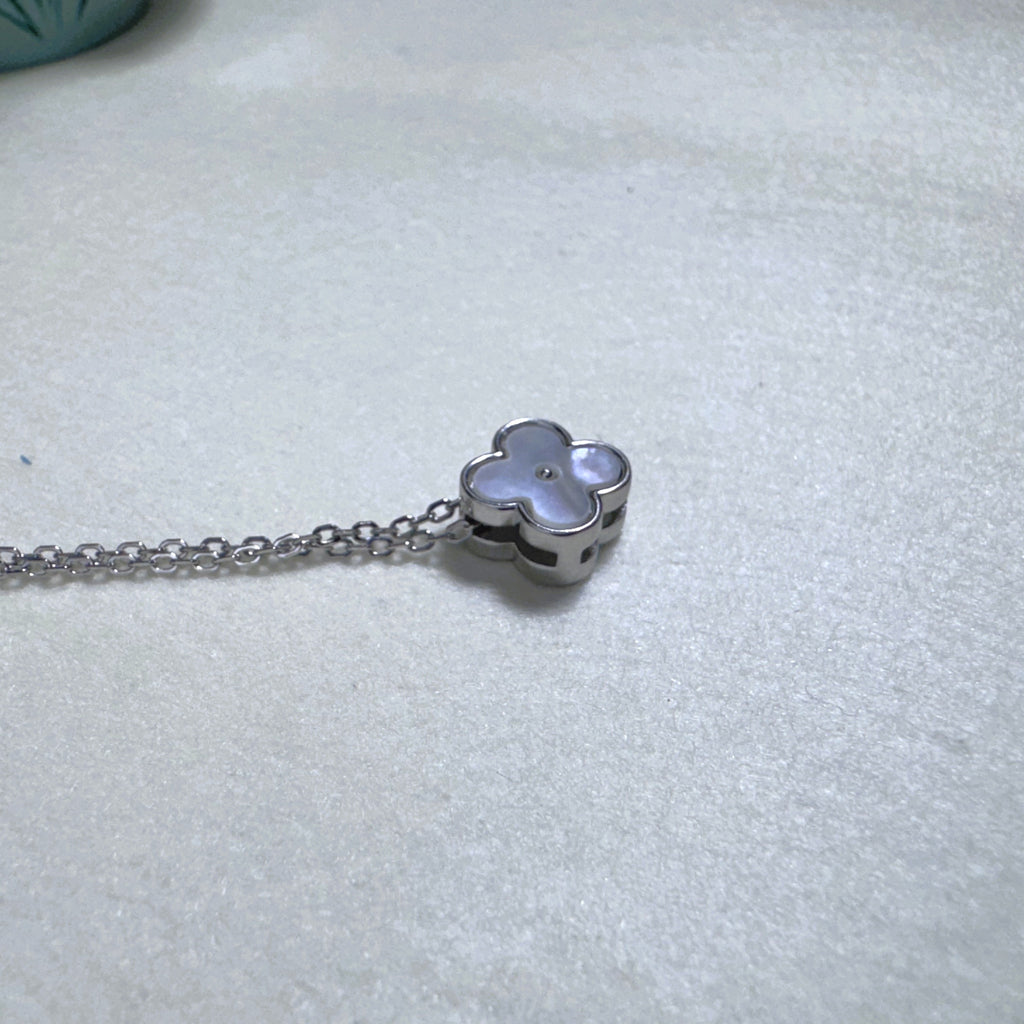 The clover slider lying on its side on the chain, showing the polished silver edge.