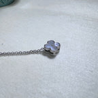 The clover slider lying on its side on the chain, showing the polished silver edge.