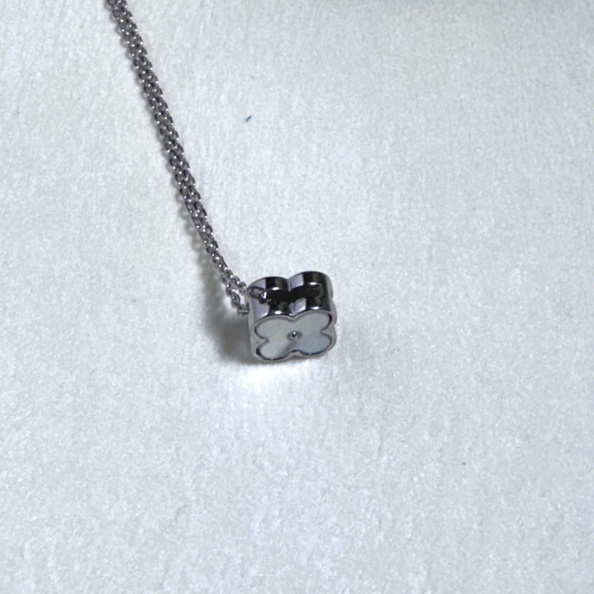 The clover turned to show its other face on the silver chain.