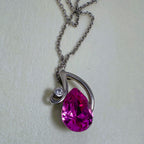 Sterling silver pendant necklace with a large pink pear cut glass stone in a swirl setting, on a cable chain.