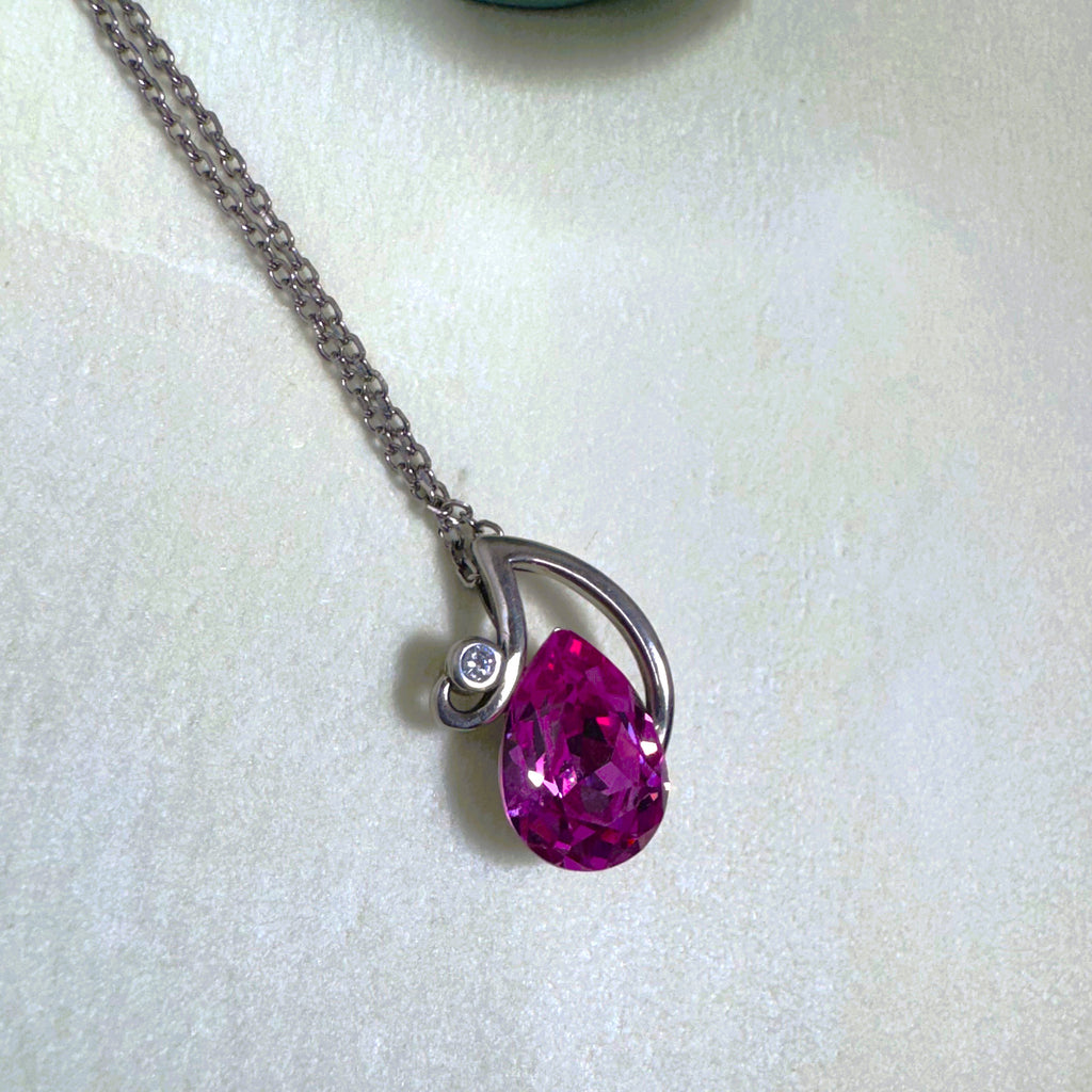 The pink pear stone pendant hanging from the silver cable chain.