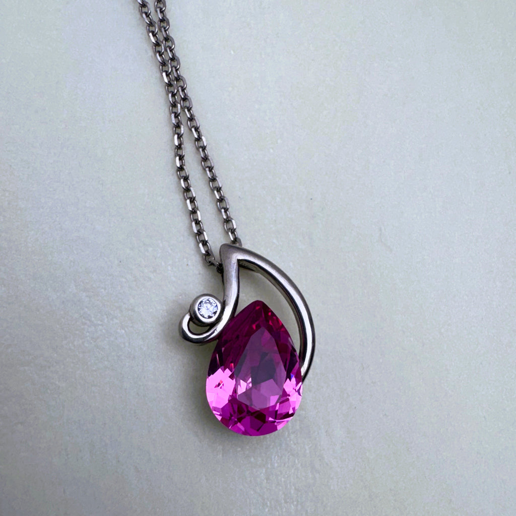 The pink stone pendant seen from the side, showing the polished swirl over the stone.