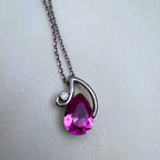 The pink stone pendant seen from the side, showing the polished swirl over the stone.