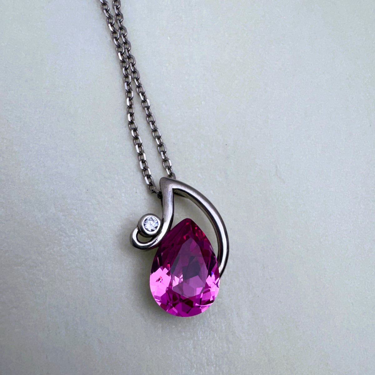 The pink stone pendant seen from the side, showing the polished swirl over the stone.