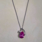 The pendant necklace laid out on a pale surface with the chain above.