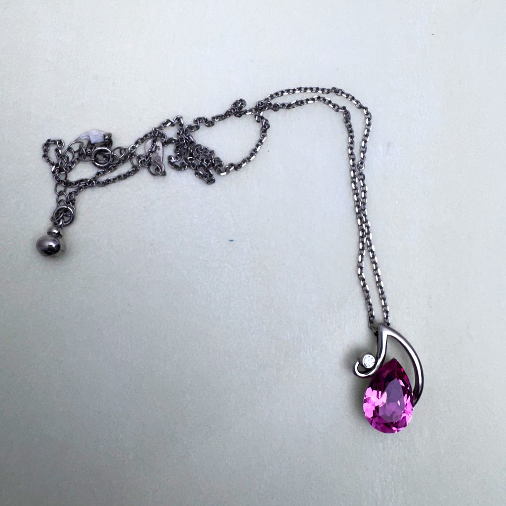 The full necklace laid out with the extender chain and the pink stone pendant.