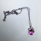 The full necklace laid out with the extender chain and the pink stone pendant.