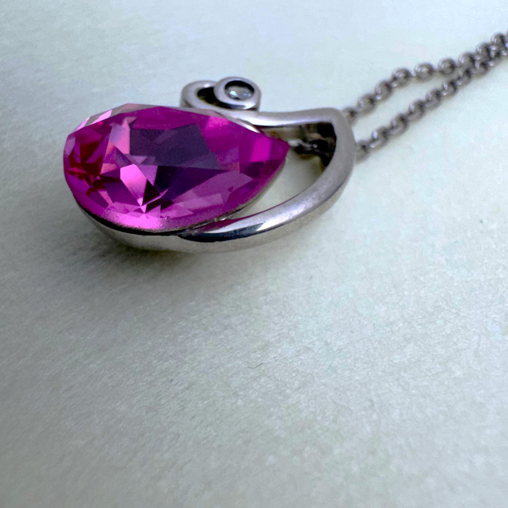 Close view of the pink pear cut stone and the small colourless stone at the tip of the swirl.