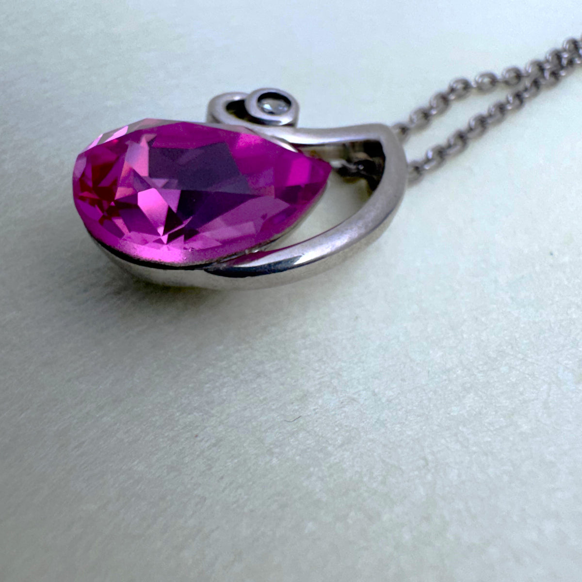 Close view of the pink pear cut stone and the small colourless stone at the tip of the swirl.