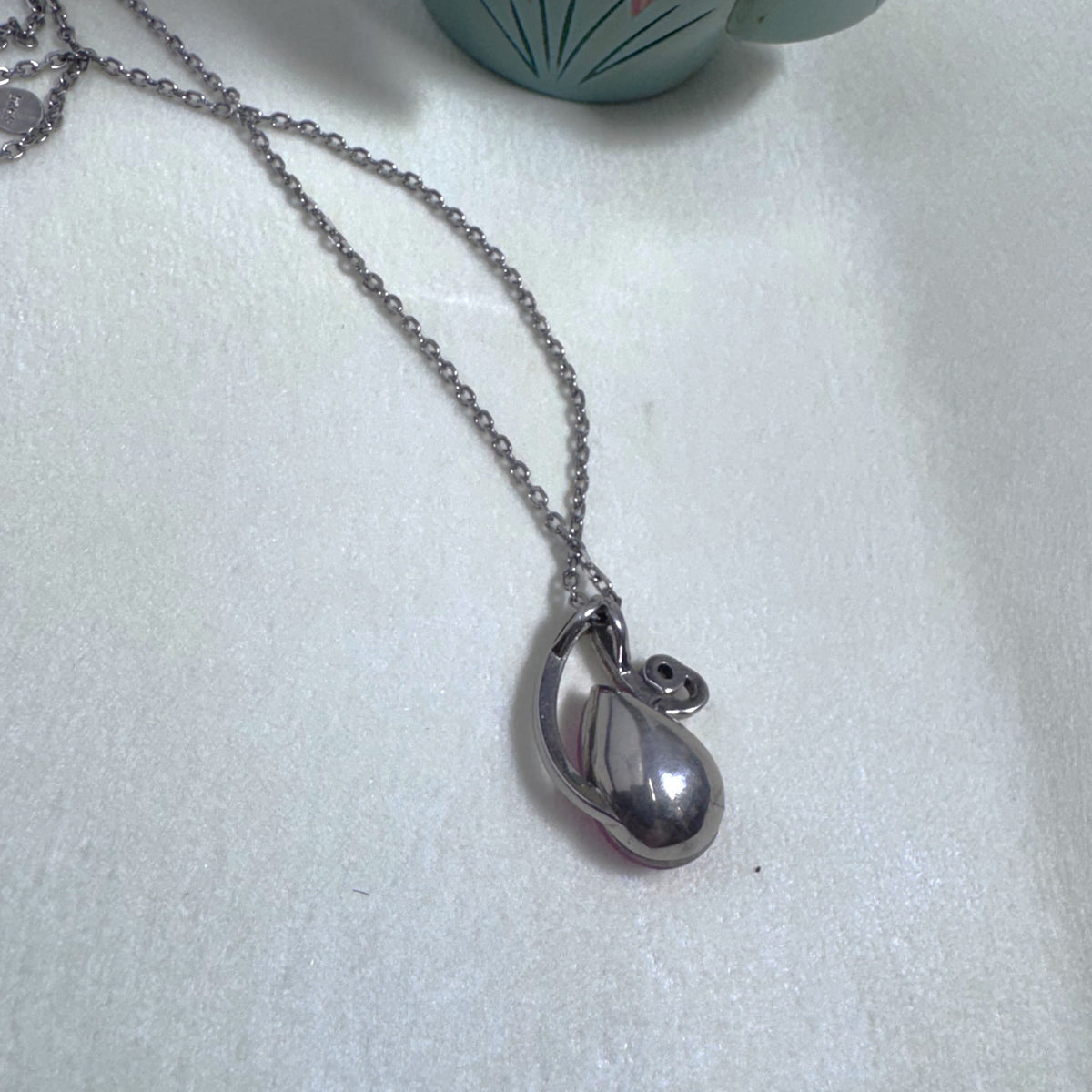The plain silver back of the swirl pendant on the chain.