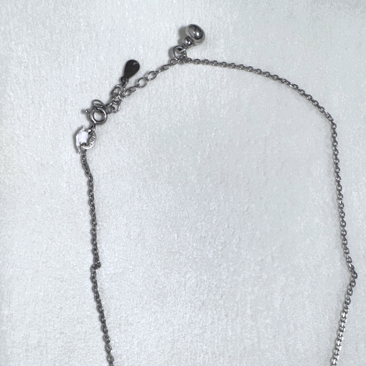 The cable chain laid out with the lobster clasp and extender chain.