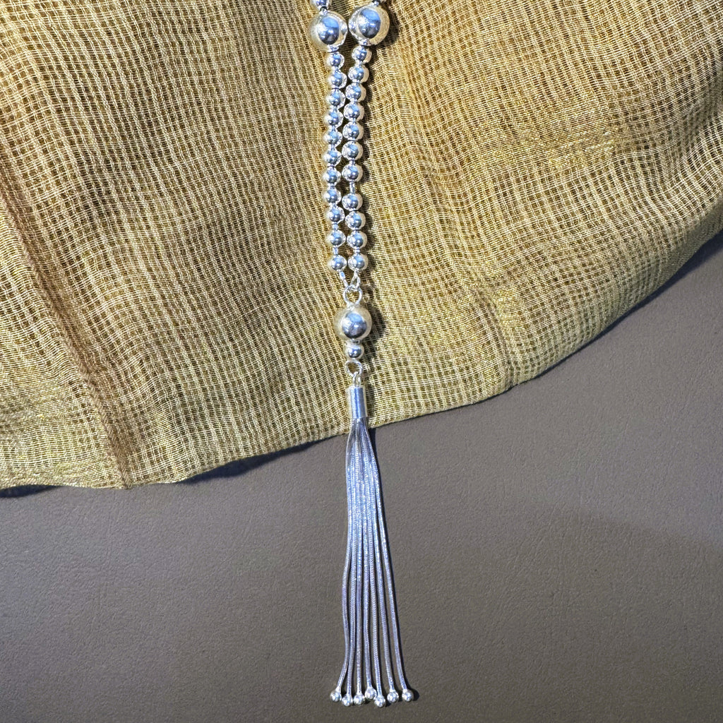 Sterling silver bead mala for Laddu Gopal with a snake chain tassel, on yellow fabric.