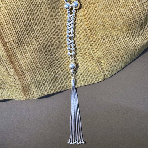 Sterling silver bead mala for Laddu Gopal with a snake chain tassel, on yellow fabric.