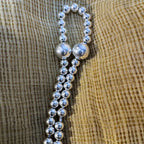 Close view of the graduated silver beads of the mala meeting at the two large front beads.