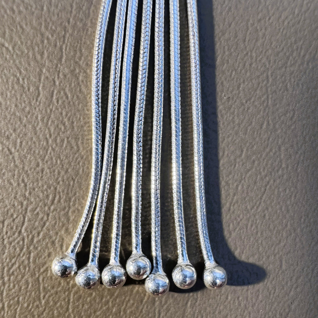 Close view of the snake chain strands of the tassel, each ending in a silver ball.