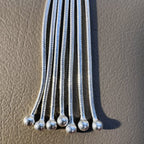 Close view of the snake chain strands of the tassel, each ending in a silver ball.