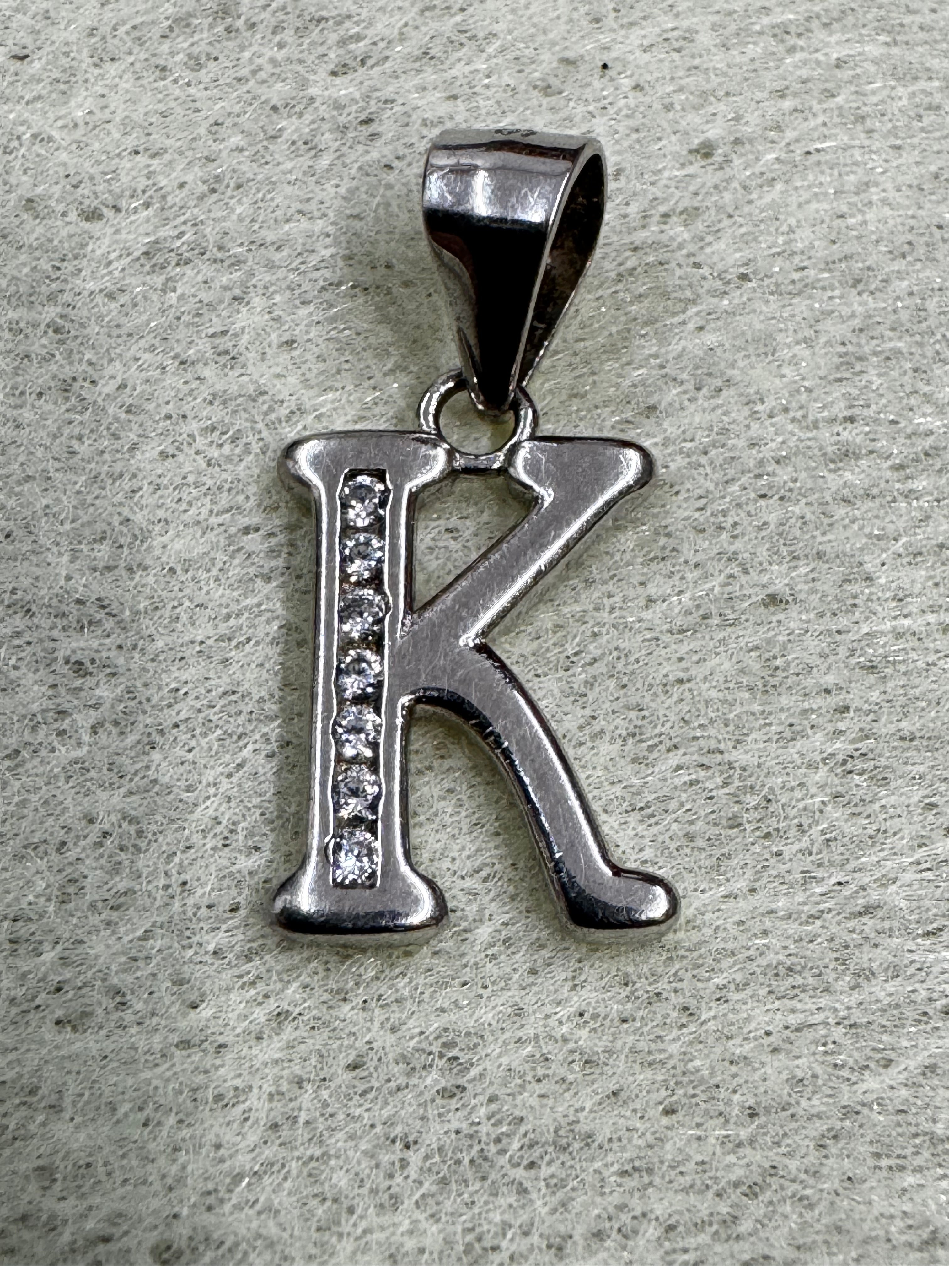 Close view of the sterling silver initial K pendant showing the channel of cubic zirconia and the tapered bail.