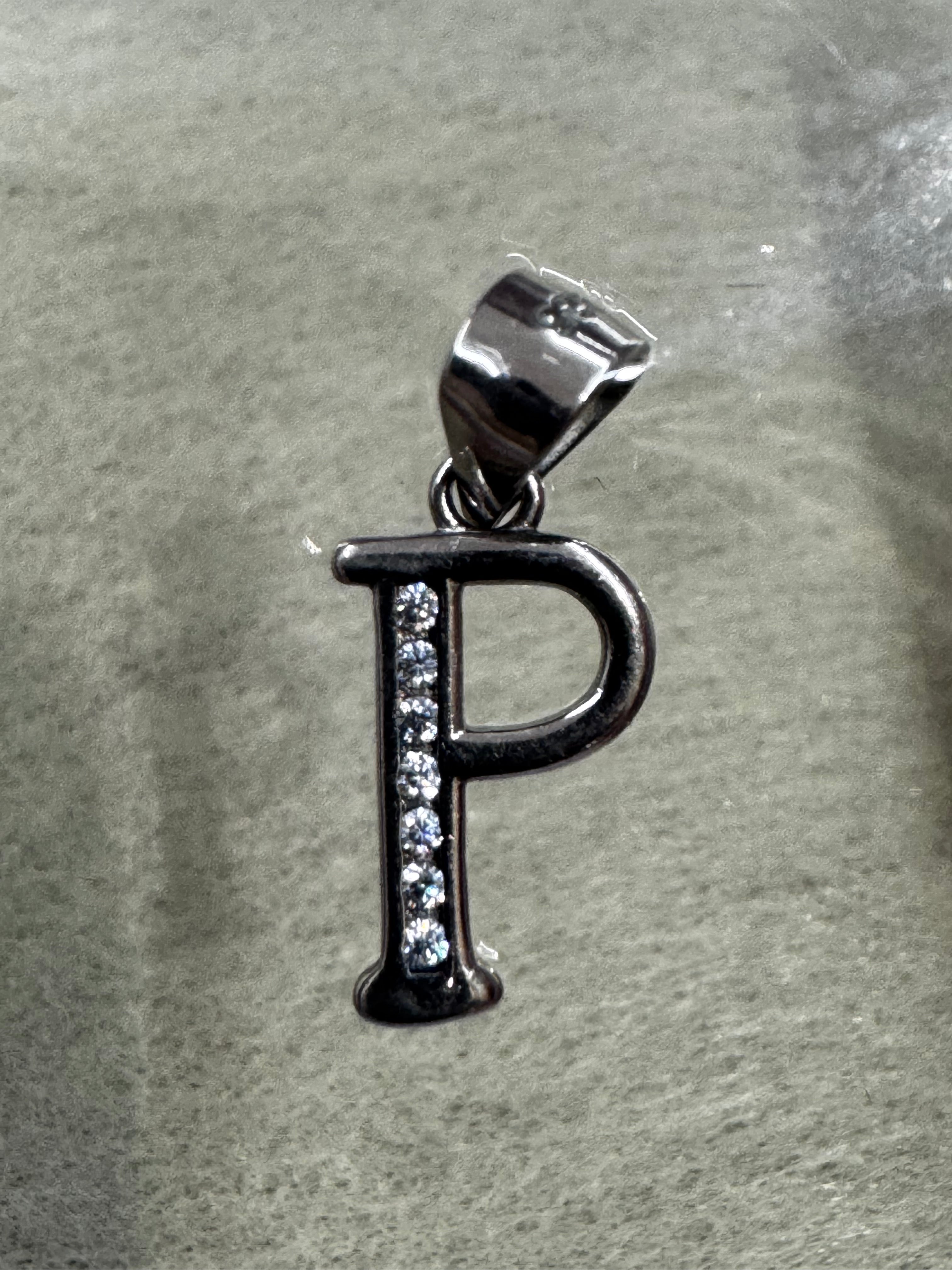 Sterling silver initial P pendant with cubic zirconia channel-set along the stem, on pale grey felt.