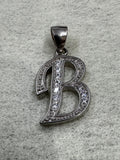 Sterling silver script initial B pendant with cubic zirconia pavé-set along its open strokes, on grey felt.