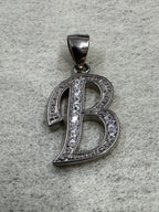 Sterling silver script initial B pendant with cubic zirconia pavé-set along its open strokes, on grey felt.