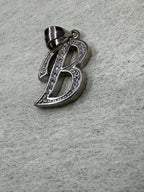 Angled view of the sterling silver initial B pendant with its tapered bail folded to one side.
