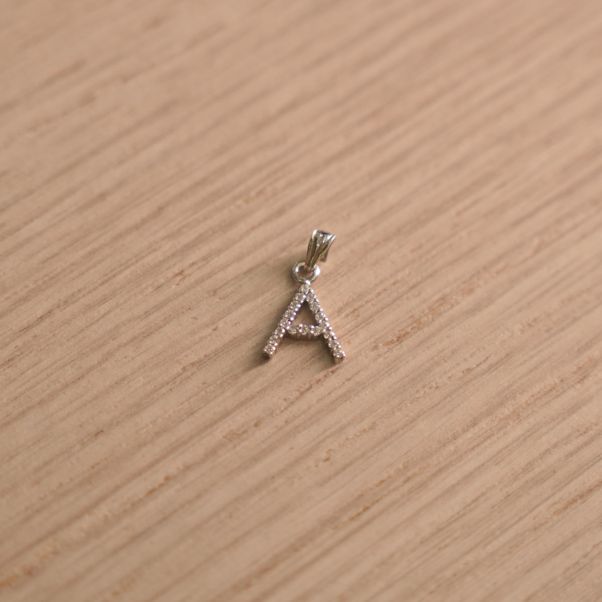 Sterling silver initial A pendant pave set with American Diamond, shown with its bail on a plain background.