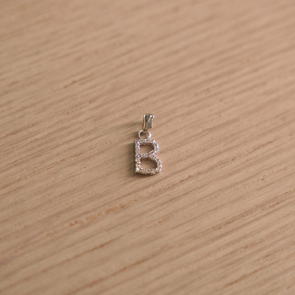 Sterling silver initial B pendant pave set with American Diamond, shown with its bail on a plain background.