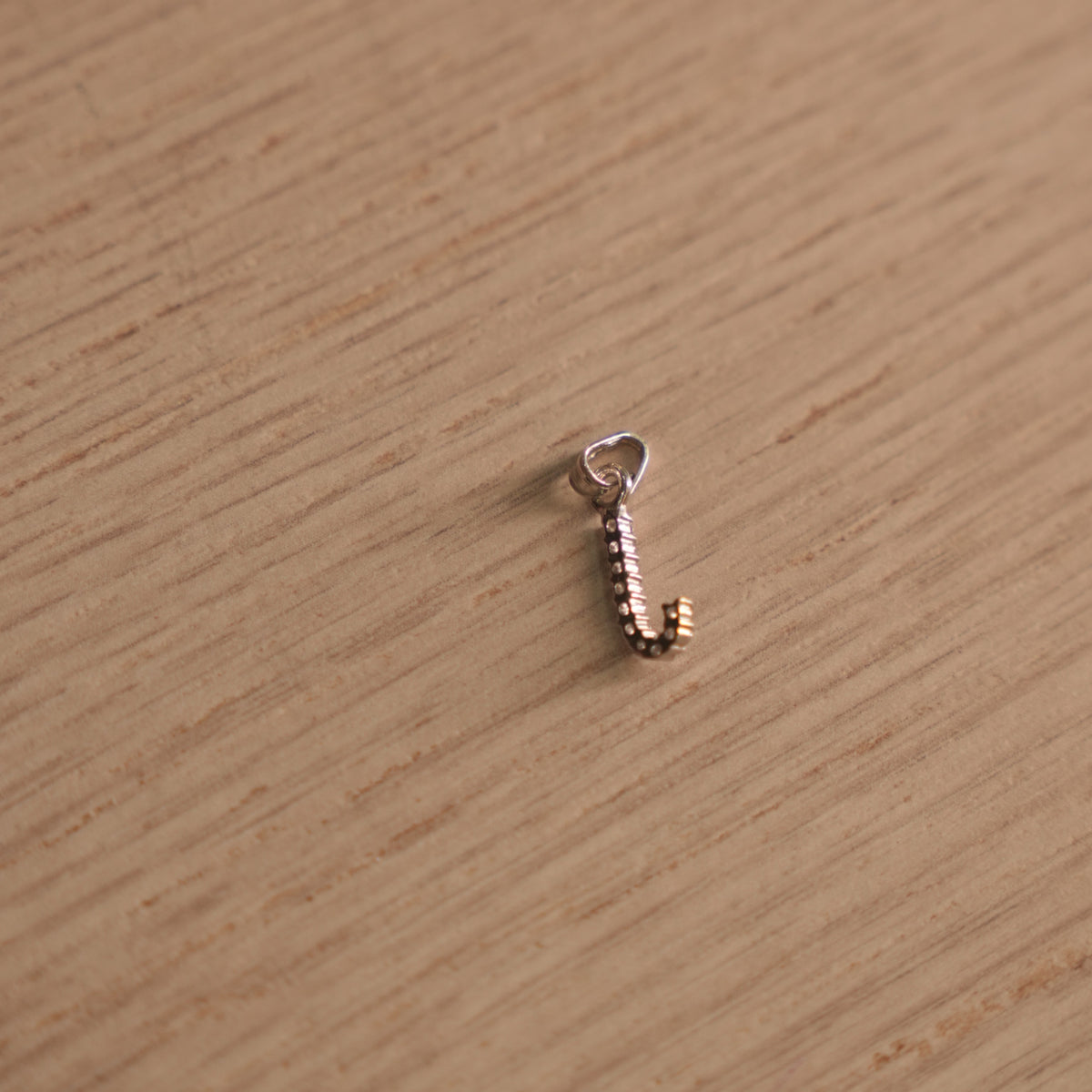 Sterling silver initial J pendant pave set with American Diamond, shown with its bail on a plain background.