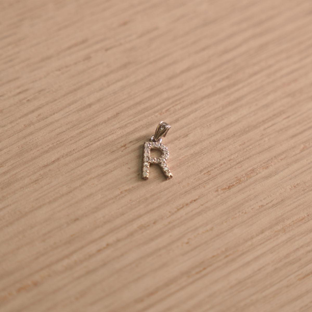Sterling silver initial R pendant pave set with American Diamond, shown with its bail on a plain background.
