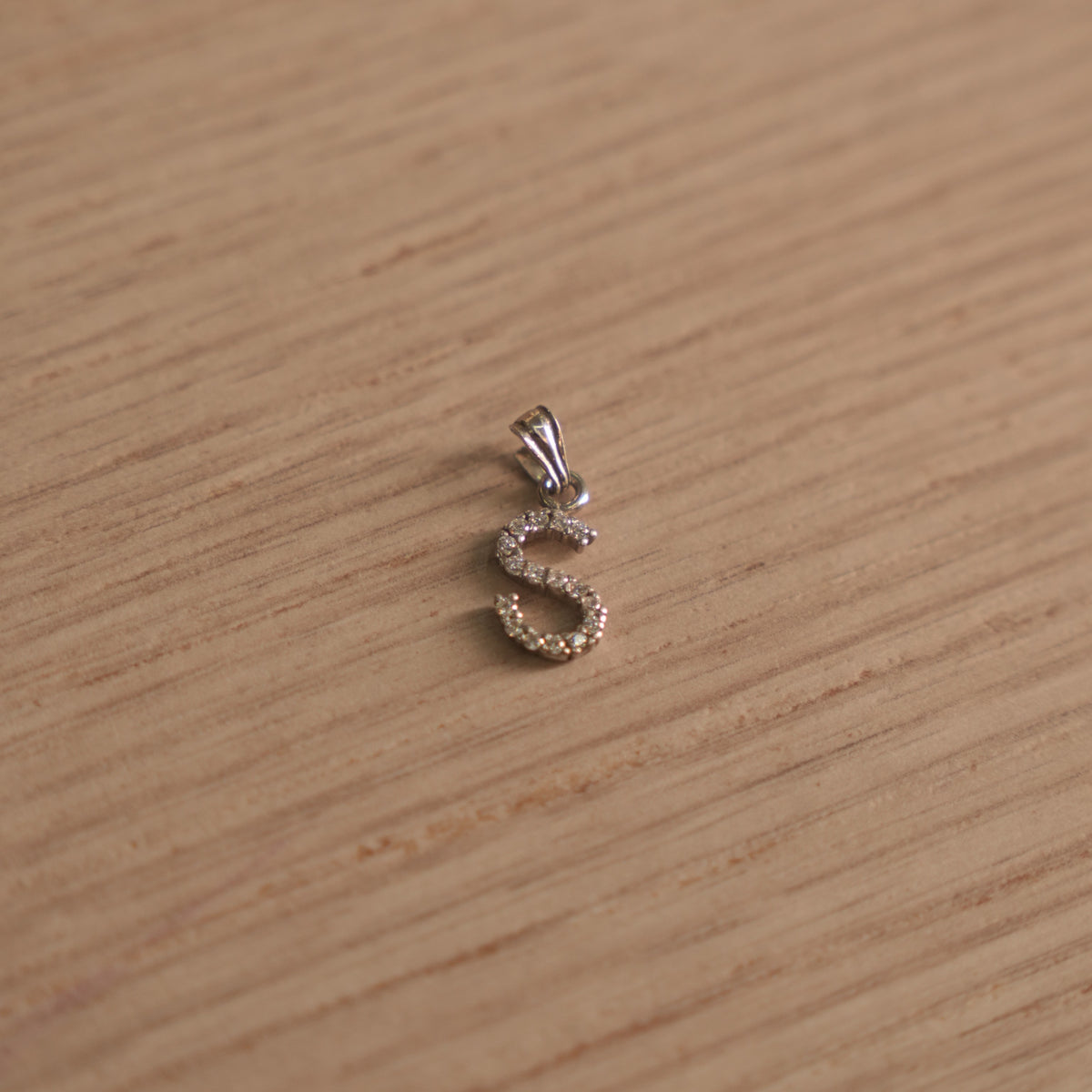 Sterling silver initial S pendant pave set with American Diamond, shown with its bail on a plain background.