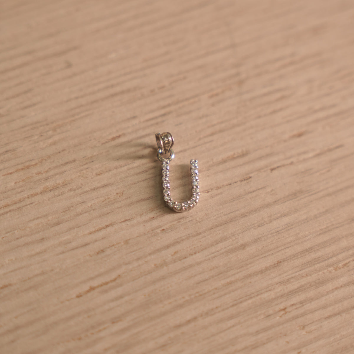 Sterling silver initial U pendant pave set with American Diamond, shown with its bail on a plain background.