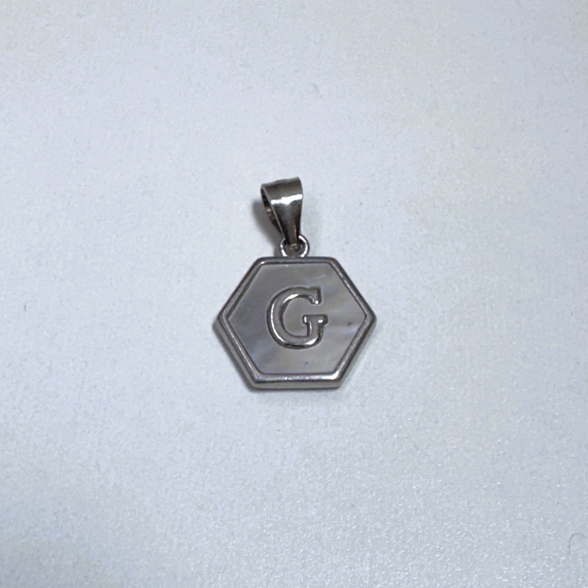 Sterling silver hexagon initial pendant with a mother of pearl face and the letter G.