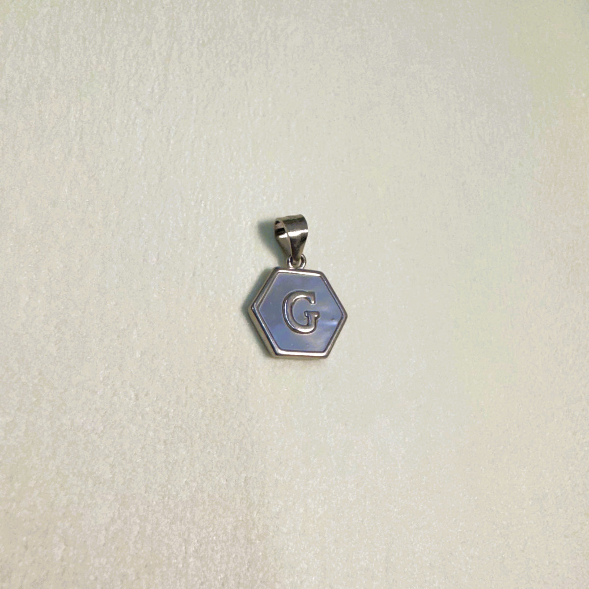 The letter G pendant seen from a slight angle.