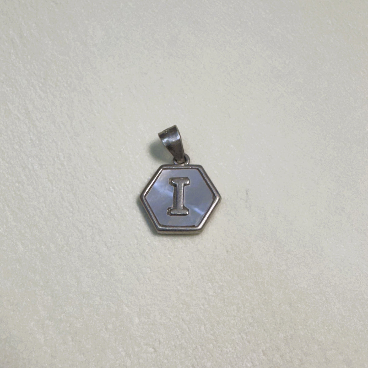 Sterling silver hexagon initial pendant with a mother of pearl face and the letter I.