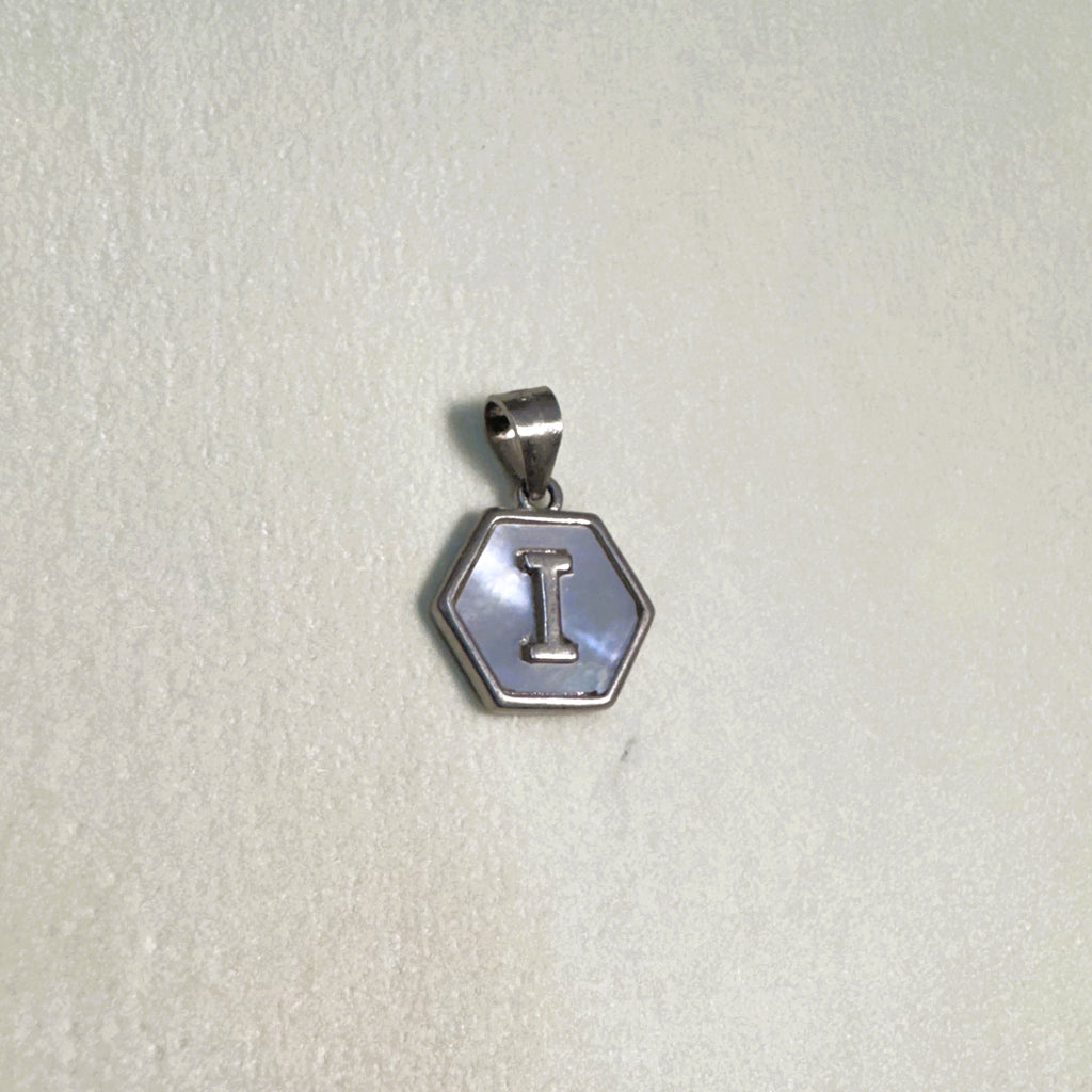 The letter I hexagon pendant on a pale surface.