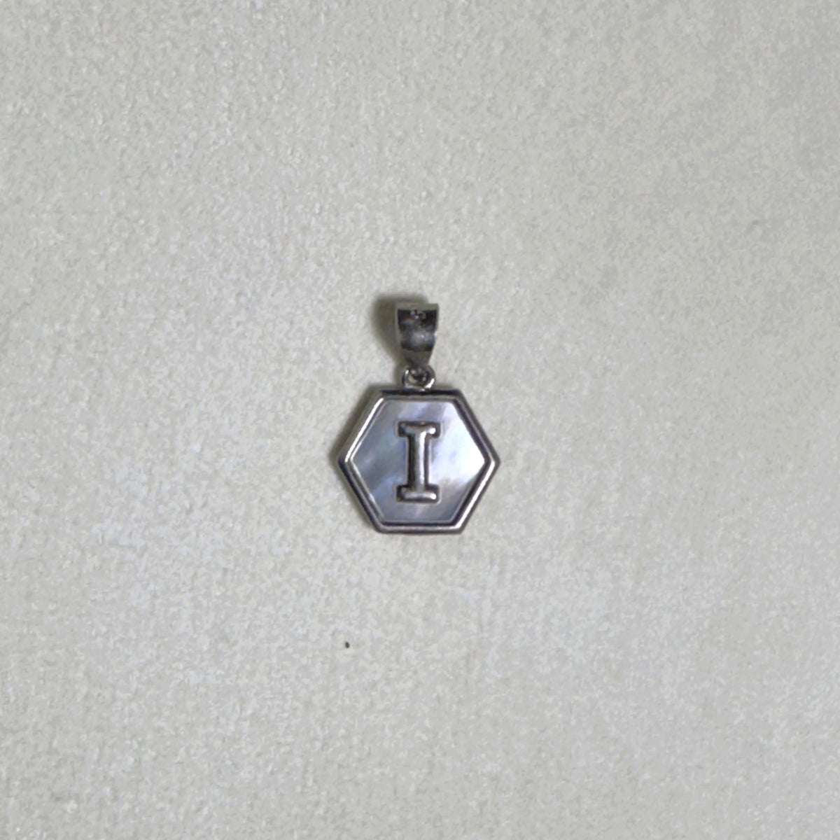 The letter I pendant seen from a slight angle.