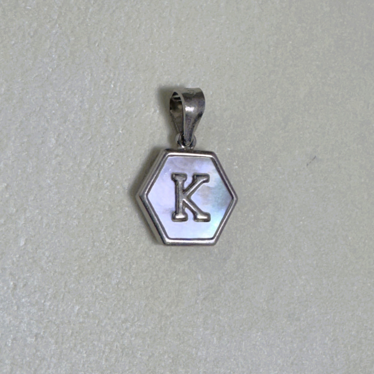 Sterling silver hexagon initial pendant with a mother of pearl face and the letter K.