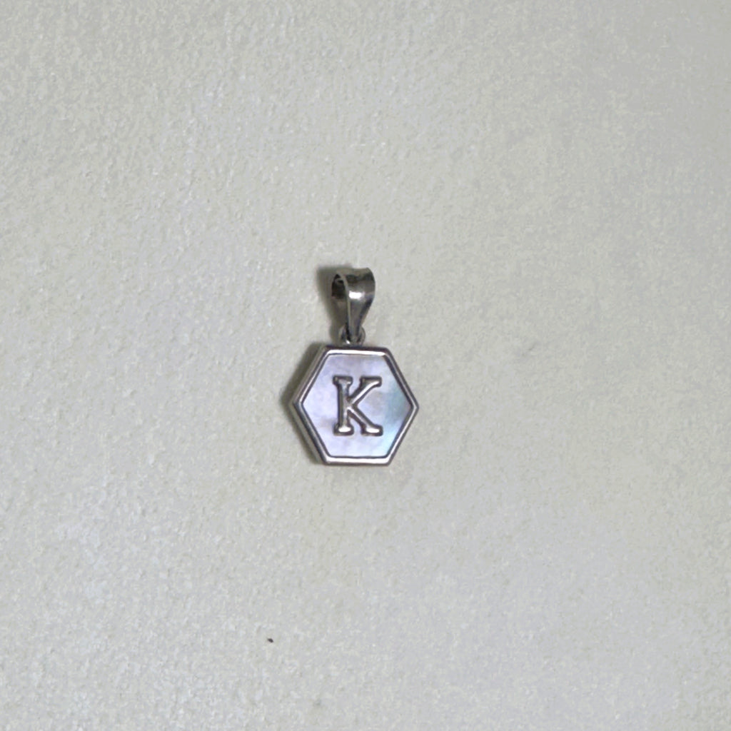 The letter K hexagon pendant on a pale surface.