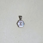 The letter K hexagon pendant on a pale surface.