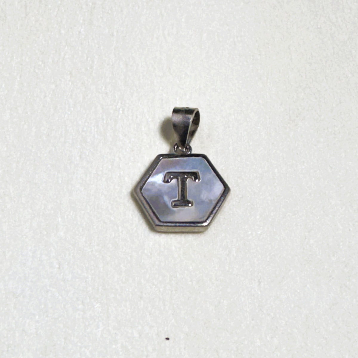 Sterling silver hexagon initial pendant with a mother of pearl face and the letter T.
