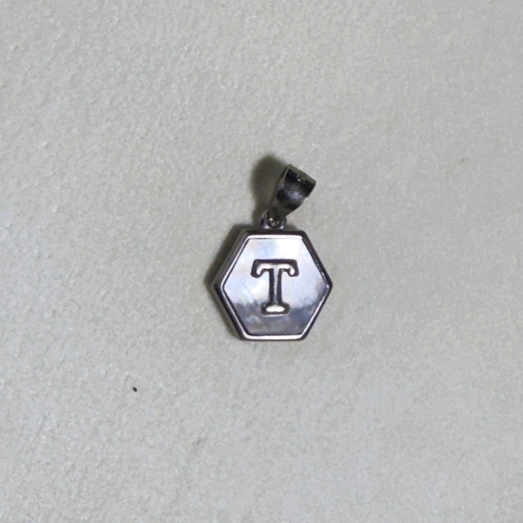 The letter T hexagon pendant on a pale surface.